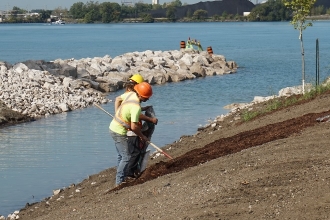 Une vue de la jetée rocheuse alors que des travailleurs préparent la rive nord du drain Broadway à une plantation et à un ensemencement améliorés