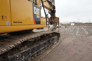 Rows of wick drains being installed using a hollow mandrel mounted on an excavator