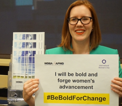 Woman holding a sign reading "I will be bold and forge women's advancement. #BeBoldforChange"
